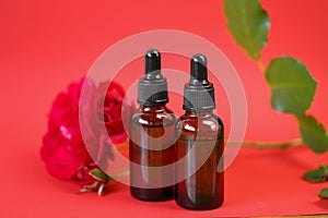 Rose essential oil. Organic rose oil in brown glass bottles set and red rose on red background.Aromatherapy and