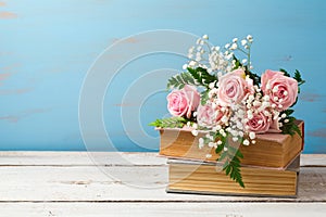 Rose flower bouquet on old books over wooden background