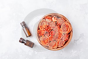 Rose flower in bowl and essential oil bottle on stone table top view. Spa, aromatherapy, wellness, beauty background.