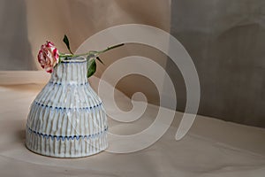 Rose flower on Copper color handmade ceramic vase and on Blush textured table cloth