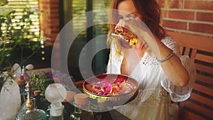 Rose flower and essential oil. Spa and aromatherapy. Woman pours essential oil into a beautiful brass bowl full of