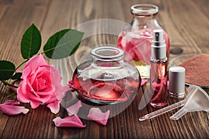 Rose flower, infused water and essential oil or rose blend bottle, flavored water in a spray bottle, pink clay powder.