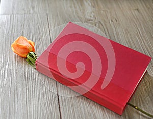 Rose flower and red hardcover book on wood background