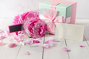 Rose flowers and gift box with bow ribbon on light table. Greeting card for Birthday, Womans or Mothers Day