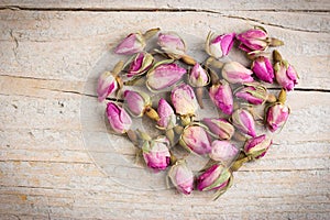 Rose flowers in heart shape on old wooden background