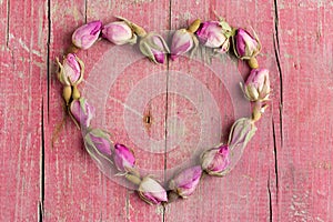 Rose flowers in heart shape on old wooden background