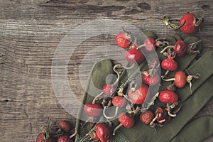 Rose hip berries, sweet briar fruits, gloves on wooden board