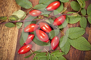 Rose hip with green leaf on wooden background