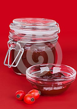Rose hip jam and fruits over red background photo