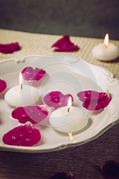 Rose hip Rosa rugosa  beach rose  Japanese rose petals floating in water with spa candles  beauty rose water concept.
