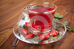 Rose hip tea with fresh fruits on wooden background