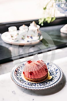 Rose and Lychee Mousses Cake decorated with rose petals in blue and white porcelain plate on marble top table