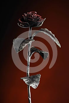 Rose made of metal on the deep-red background