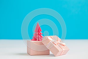 Rose origami christmas tree in form of present isolated on blue