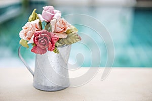 Rose paper in tin water pot with space on blurred blue background