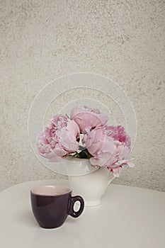 Rose peonies and a cup of coffee on a white table