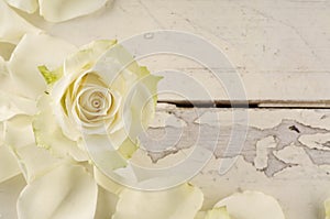 Rose and petals over wooden background.