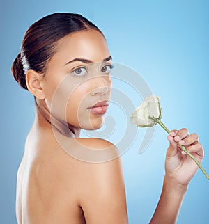 Rose, portrait and woman in studio for skincare, wellness and petal cosmetic on blue background. Face, flower and girl