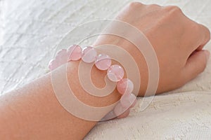 Rose quartz bracelet on woman wrist.