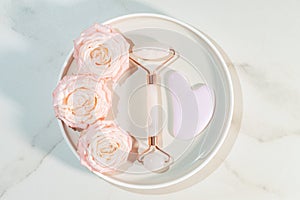 Rose quartz face roller for face skin treatment. Anti aging and toning effect. Massaging with a stone. Trendy