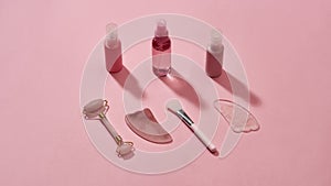 Rose quartz facial massage tools gua sha stone scrapers, face roller and beauty products in plastic bottles isolated on