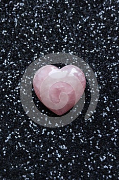 rose quartz heart on black glitter background, valentine\'s day concept.