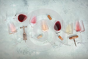 Rose, red, and white wine glasses, with corkscrews and corks, overhead flat lay