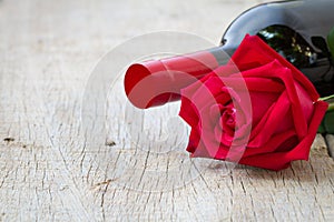 Rose with red wine bottle on wooden. Valentine's day, anniversar