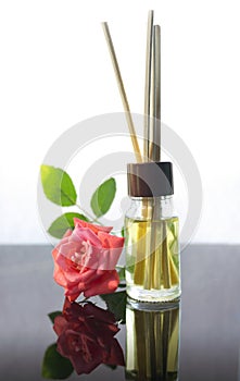 Rose scented oil bottle with wooden sticks on white
