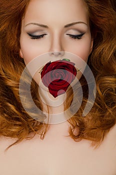 Rose in the teeth of woman with long hair