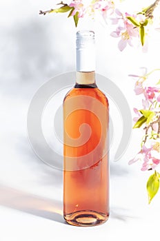Rose wine bottle on the white table and pink flowers. Rosado, rosato or blush wine tasting in wineshop, bar concept. Copy Space photo