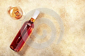 Rose wine glass with bottle on the beige table. Copy Space, top view photo
