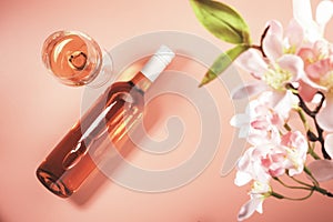 Rose wine glass with bottle on blush background and pink flowers. Rosado, rosato pink wine tasting photo
