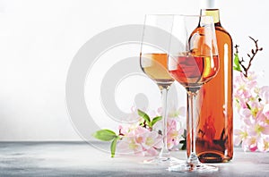 Rose wine glass and bottle on the gray table and pink flowers. Rosado, rosato or blush wine tasting photo