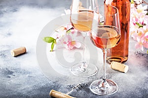 Rose wine glass with bottle on the gray table and pink flowers. Rosado, rosato or blush wine tasting in wineshop, bar concept. photo