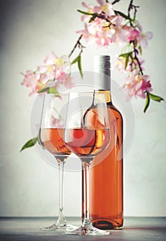 Rose wine glass and bottle on the gray table and pink flowers. Rosado, rosato or blush wine tasting photo