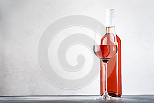 Rose wine glass with bottle on the gray table. Pink rosado, rosato or blush wine tasting in wineshop, bar concept. Copy Space