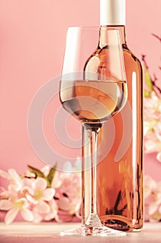 Rose wine glass with bottle and pink flowers. Rosado, rosato or blush wine tasting in wineshop, bar concept. Copy Space photo