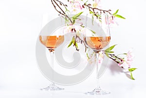Rose wine glass with bottle on the white table and pink flowers. Rosado, rosato or blush wine tasting in wineshop, bar concept.
