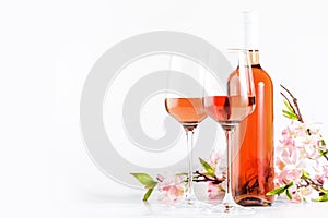 Rose wine glass with bottle on the white table and pink flowers. Rosado, rosato or blush wine tasting in wineshop, bar concept.