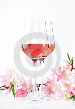 Rose wine glass with bottle on the white table and pink flowers. Rosado, rosato or blush wine tasting in wineshop, bar concept.