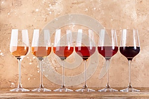 Rose wine glasses assortment on wine tasting. Degustation different varieties, colors and shades of pink wine concept. Beige photo