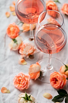Rose wine in glasses and roses on white background, flat lay