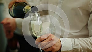 Rose wine is poured into a glass in the hands of a waiter. Media. Close-up of bottle neck pouring into bowl. Slow motion