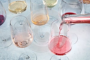 Rose wine poured into a glass at a tasting at a winery. Various colors of wine