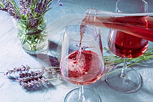 Rose wine, pouring from a bottle into a glass, with lavender flowers