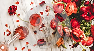 Rose wine pouring from bottle to glass and ranunculus flowers