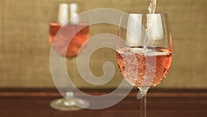 Rose wine pouring into glass on wooden table