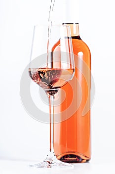 Rose wine pouring out of the bottle, white background. Rosado, rosato or blush wine tasting in wineshop, bar concept. Copy Space