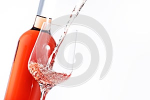 Rose wine pouring out of the bottle, white bakcground. Rosado, rosato or blush wine tasting in wineshop, bar concept. Copy Space